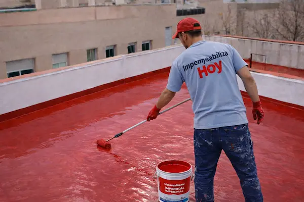 Personal aplicando impermeabilizante profesional en terraza de concreto